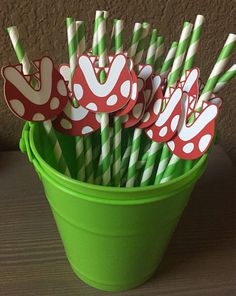 green bucket filled with paper straws topped with red and white polka dot decorations on them