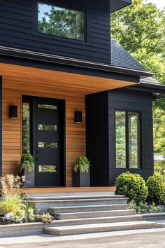 a black house with two large windows and steps leading up to the front door area