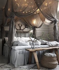 a canopy bed with lights hanging from it's sides and pillows on the floor