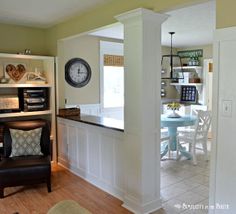 a living room filled with furniture and a clock on top of a shelf next to a doorway