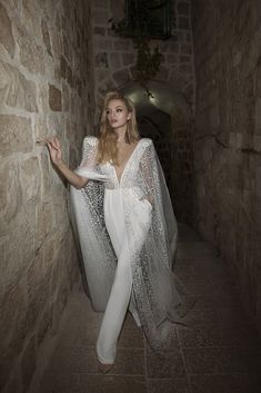 a woman in white is walking down an alley way