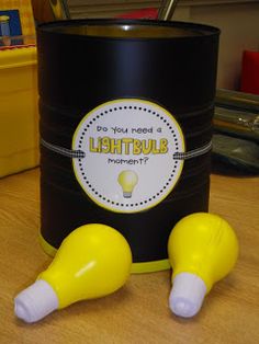 a yellow lightbulb sitting on top of a table next to a black can