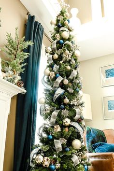 a decorated christmas tree in the corner of a living room with blue and white decorations