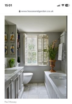 an image of a bathroom setting with white furniture and decor on the walls, along with a window that has shutters open to let in natural light