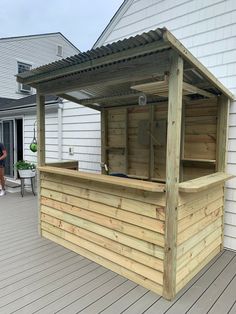 a wooden bar on a deck next to a white house with people standing around it