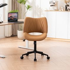 a brown office chair sitting on top of a hard wood floor next to a laptop computer