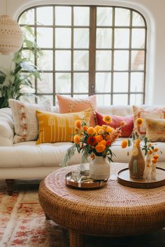 a living room filled with furniture and flowers in vases on top of a coffee table