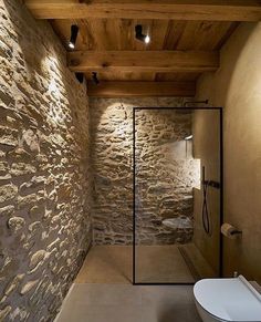 a bathroom with stone walls and wooden ceiling