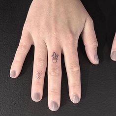 two fingers with tattoos on them, one has a hand and the other has a heart