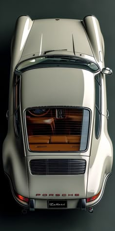 the rear end of an old car with its hood up and lights on, in front of a black background