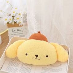 a yellow stuffed animal with a brown hat on it's head sitting in a white box