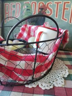 a red and white checkered table cloth in a wire basket on top of a doily