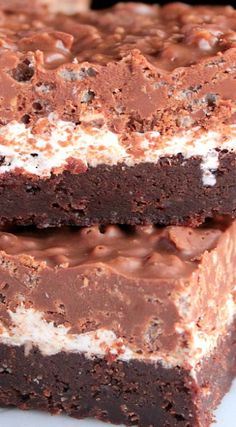 two chocolate brownies with white frosting on top and one has been cut in half