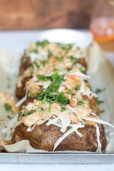 two baked potatoes topped with parmesan cheese and garnish