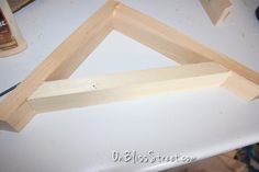 some wood is laying on top of a white table and there are two pieces of wood in the shape of a triangle