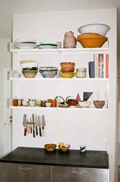 the shelves are filled with dishes and utensils