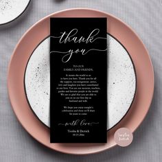 a black and white wedding thank card on a pink plate next to two silverware