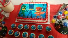 a birthday cake and cupcakes are on a red tablecloth with other decorations