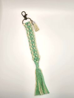 a green and white tasseled keychain hanging from a hook