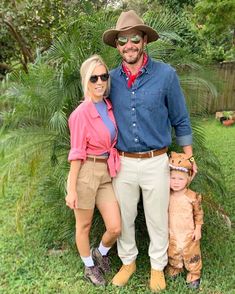 a man and woman standing next to each other in the grass with a small child