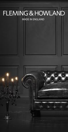 a black leather couch with candles on the floor in front of an ornate wall and chandelier