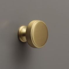 an image of a door knob on a grey wall with the handle in gold color