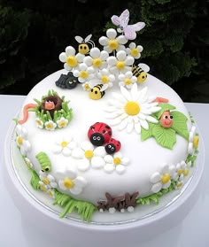 a cake decorated with daisies, ladybugs and bugs