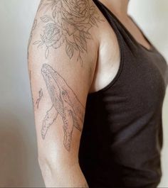 a woman with a rose tattoo on her arm and shoulder is standing in front of a white wall