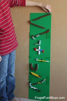 a young boy standing in front of a green lego board that is made out of legos