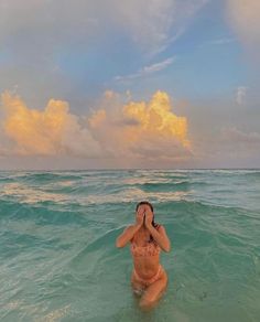 a woman standing in the ocean with her eyes closed