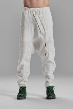 "DISTORTED BOILED LINEN DROPPED CROTCH TROUSERS WITH ELASTIC WAISTBAND__ These contemporary boiled linen trousers are created to escape the mainstream similarly. A distorted front is offset by two irregular pockets on the back, asymmetrically positioned on different levels, and J shaped, arched legs, cause the pants to stay very bunched up, embodying the most brutally urban and masculine silhouette__ who__ Conceptual Thinker when__ Cool Evenings where__ From The Studio To An Underground Party mo White Full Length Pants With Belt Loops, White Full-length Bottoms With Belt Loops, White Baggy Full-length Parachute Pants, Fitted White Pants With Pockets, White Linen Full-length Bottoms, White Bottoms With Pockets And Loose Fit, Baggy White Parachute Pants With Pockets, White Baggy Parachute Pants With Pockets, White Straight Pants With Belt Loops