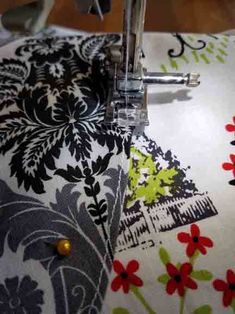 the sewing machine is on top of the fabric with flowers and leaves printed on it