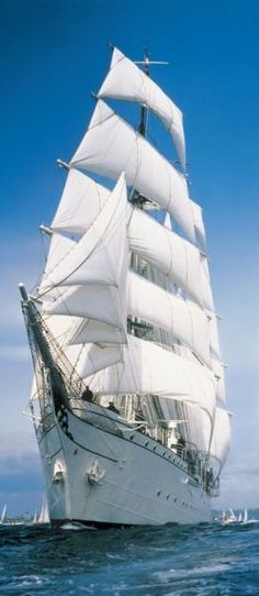 a large white sail boat sailing in the ocean with lots of sails on it's side