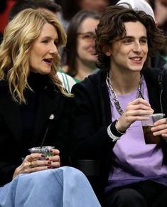 two people sitting next to each other in front of an audience at a basketball game