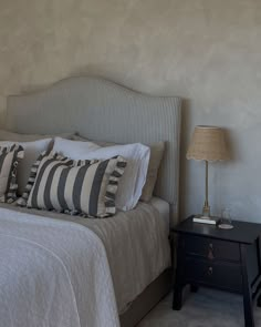 a bedroom with a bed, night stand and two lamps on either side of the bed