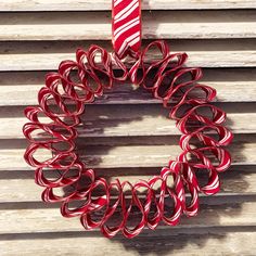 a red and white christmas wreath hanging on the side of a wooden wall with slatted shutters