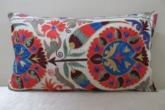 a decorative pillow is sitting on a white surface with an orange and blue flowered design