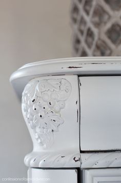 an old white dresser with ornate carvings on the doors and drawer knobs is shown in this close up photo