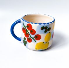 a ceramic cup with fruit painted on it