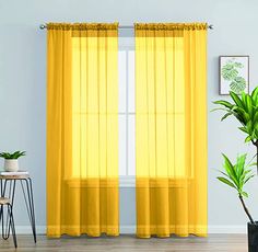 a living room with yellow curtains and a potted plant