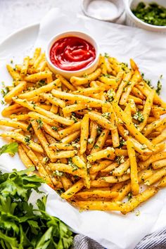 french fries on a plate with ketchup and parsley next to it, ready to be eaten