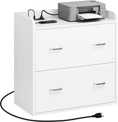 a printer is sitting on top of a filing cabinet with two drawers and a power cord