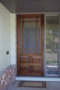 the front door is made of wood and has two glass panels on each side, along with a brick step leading up to it