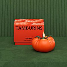 an orange pumpkin sitting next to a box of tamburins on a green surface