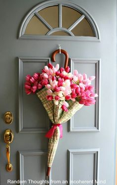 a bouquet of flowers is hanging on the front door with an umbrella attached to it