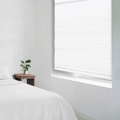 a bed with white sheets and pillows next to a window in a room that has no curtains