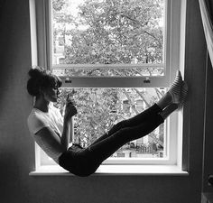 a woman sitting in a window sill with her legs crossed and feet up on the windowsill