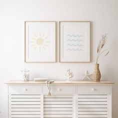 two framed pictures hang above a white dresser