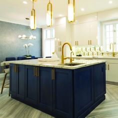 a large kitchen with an island in the middle and gold fixtures hanging from the ceiling