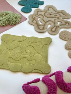 various rugs are arranged on a table with pink, green and blue decorations in the middle